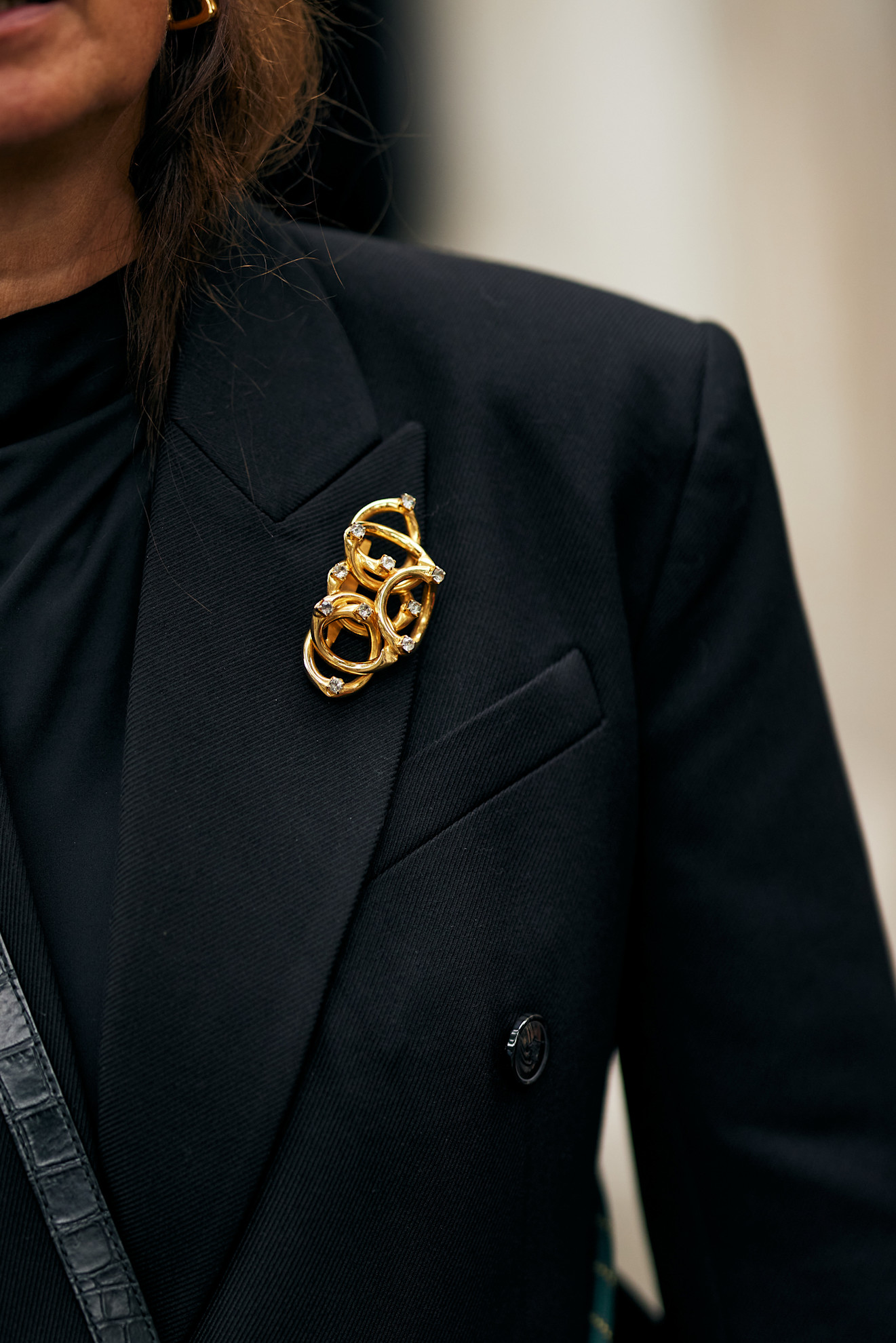 woman wearing a gold brooch and a black blazer in Paris