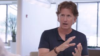 An image of Todd Howard in the middle of explaining a concept using hand gestures.