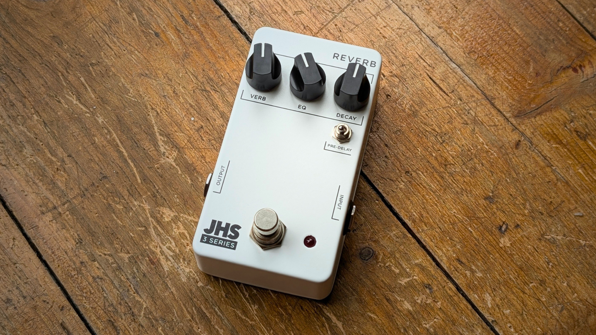 A JHS 3 Series Reverb pedal on a worn wooden floor