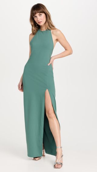 moderl wears green low back halter dress with slit and silver heels