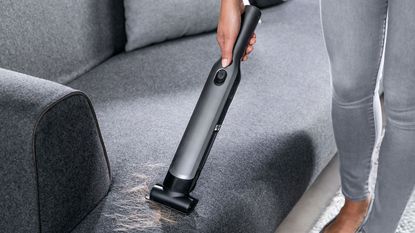 woman holding a Shark Cordless Handheld Vacuum WV200UK vacuuming up hair on a sofa