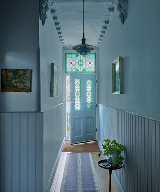 hallway color-drenched mid-blue with traditional front door and ceiling moldings