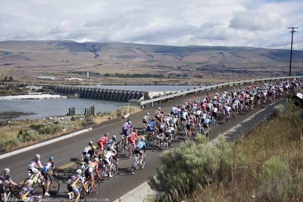 Riders pass a dam on the Columbia River as the men's field rolls out of The Dalles.