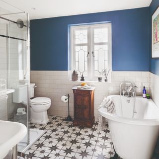 A blue-painted bathroom with patterned tiles and a bathtub