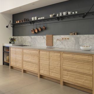 Mixed material kitchen by Roundhouse design with wood base units and stone and grey walls