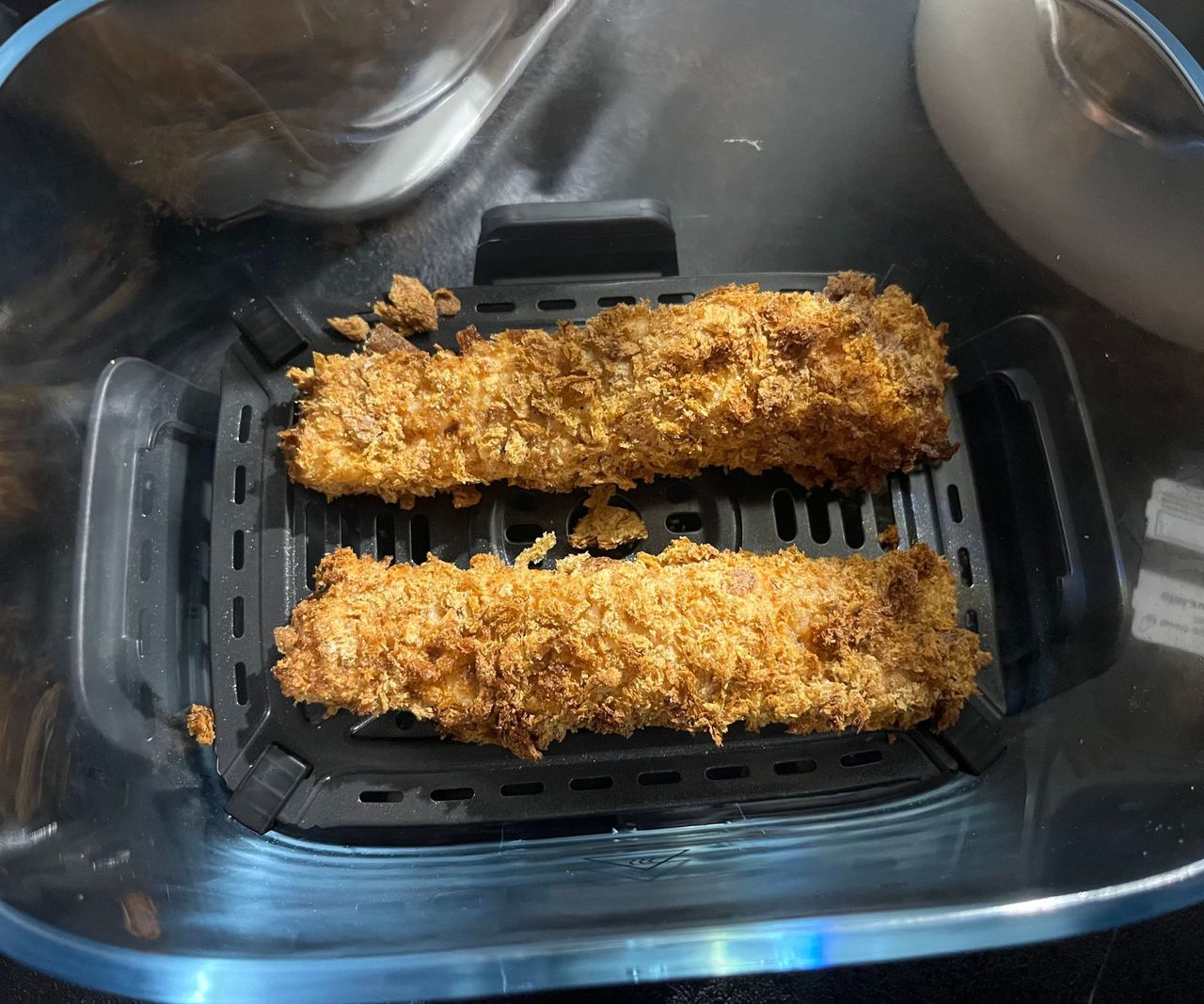 Two toasted breaded salon fillets in a glass air fryer basket
