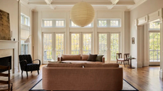living room with two couches facing each other, a large paper ceiling light, and a wall of windows and doors with no curtains