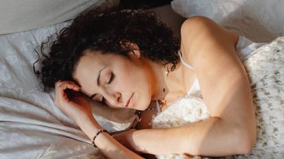 Woman napping in bed, sleep & wellness tips
