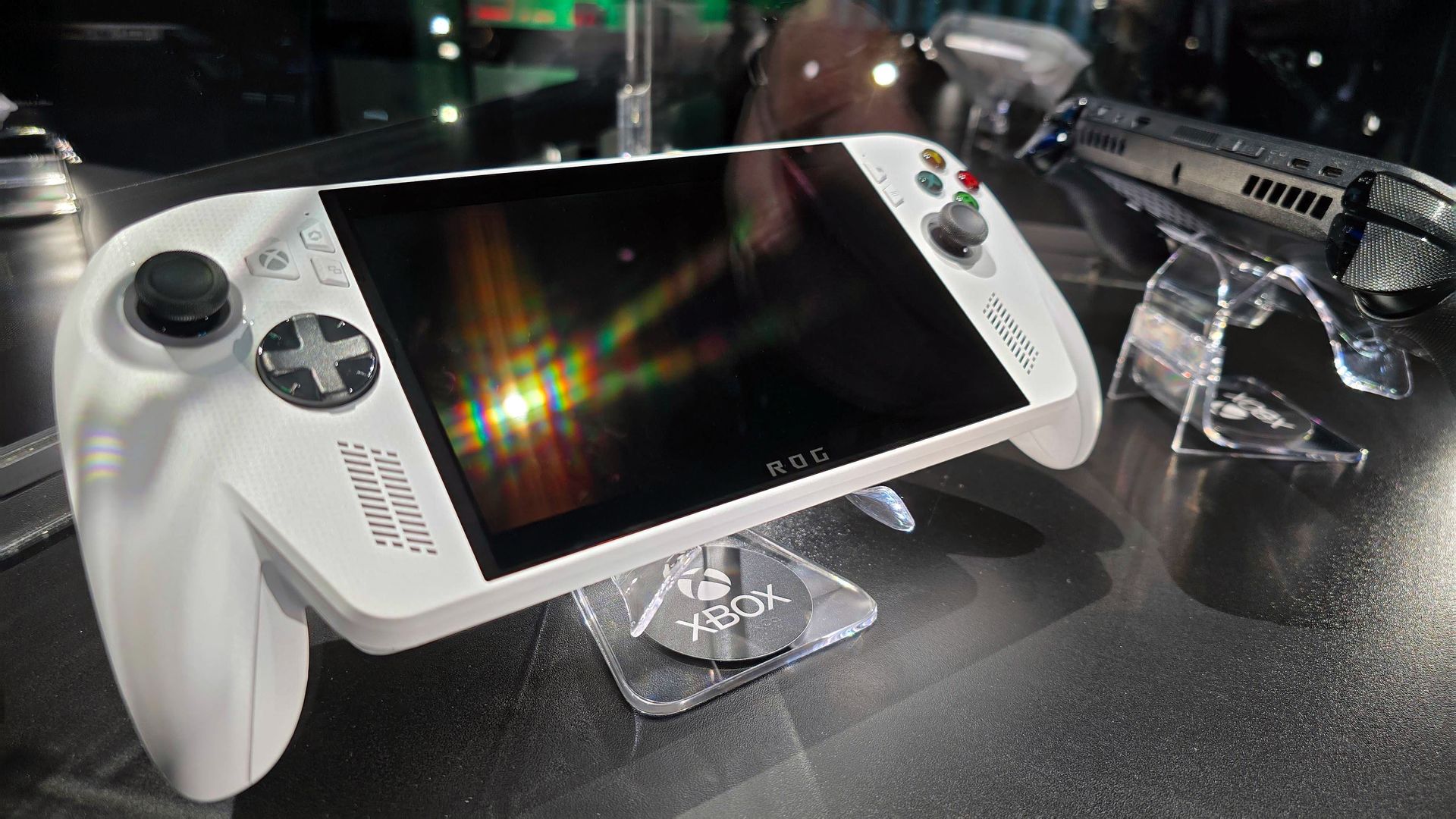 ASUS ROG Xbox Ally (white) and ROG Xbox Ally X (black) in a glass display case at Gamescom in August, 2025.