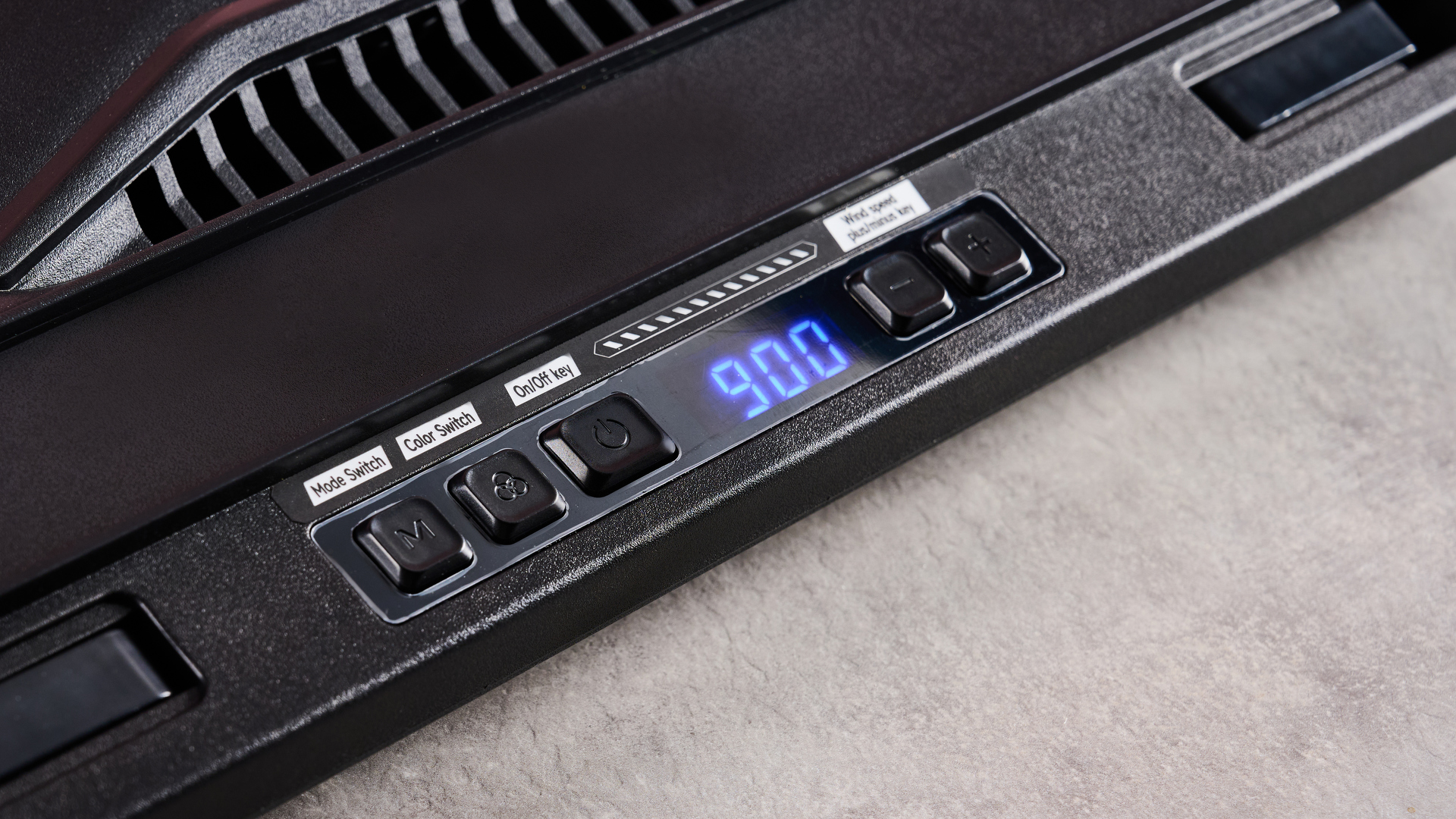 A closeup of the Llano V10 Gaming Laptop Cooling Pad's controls, showing a lighting mode switch, color switch, on/off switch, fan speeds switches and an LCD panel showing its 900rpm fan speed.