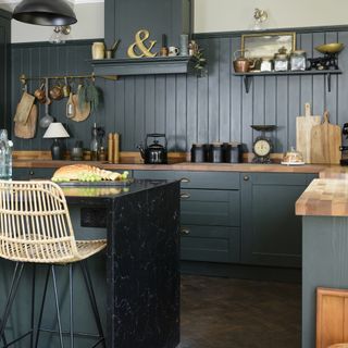 Green kitchen with wall panelling and waterfall worktop on peninsula