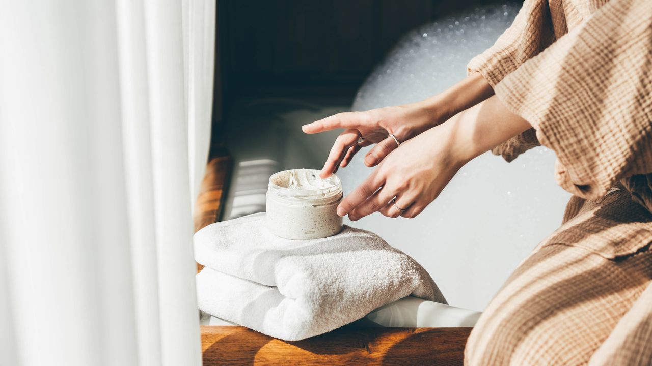 Close up of woman&#039;s hands using tub of moisturiser