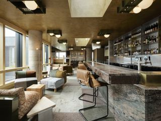 A hotel bar area made of natural stone with colourful seating