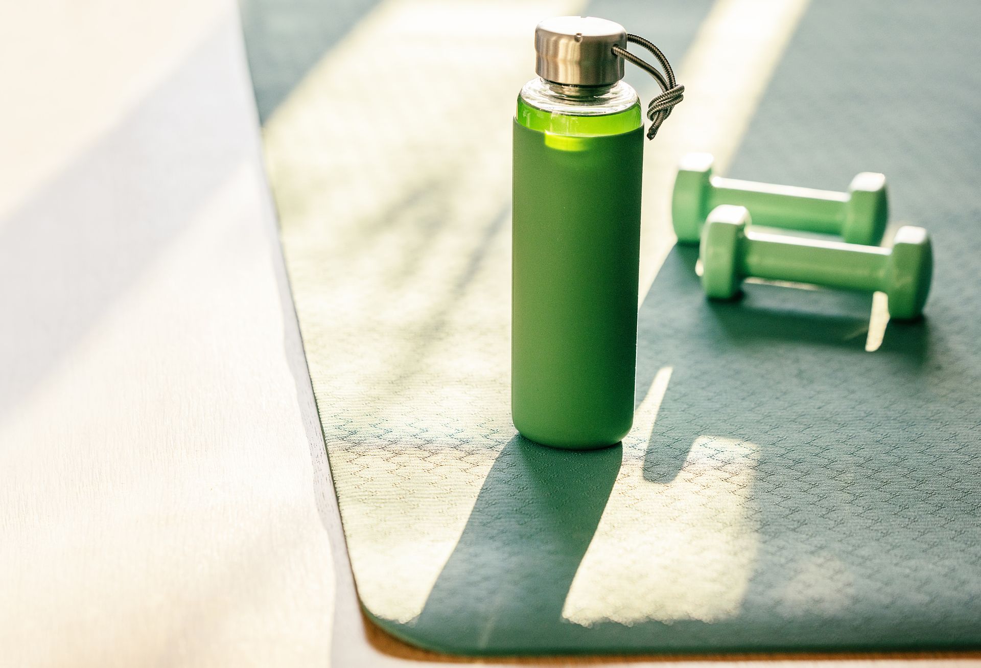 water bottle and dumbbells on a mat