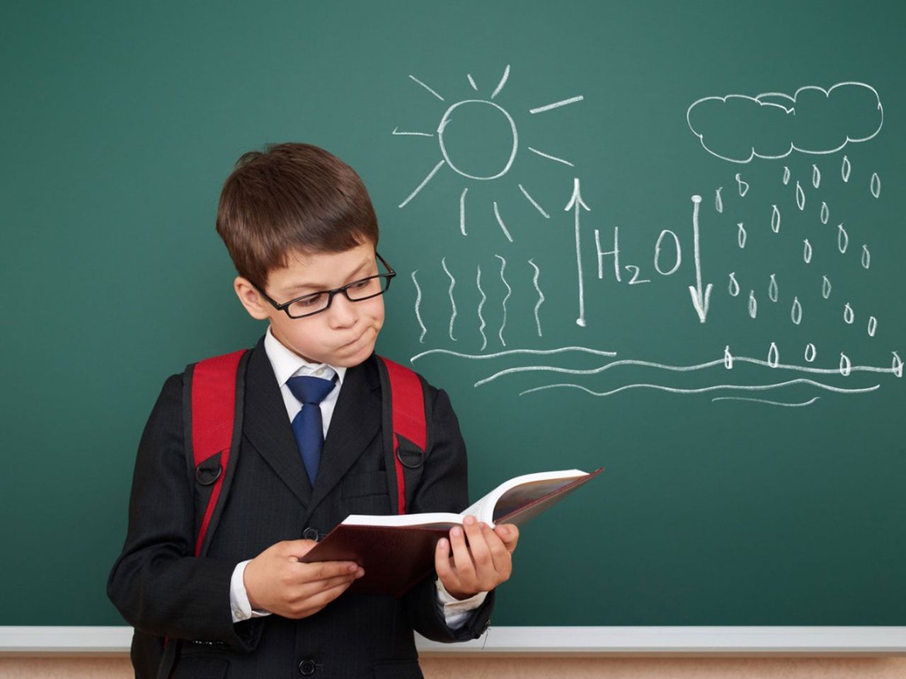 Kid Reading A Book And The Water Cycle Written On A Chalkboard