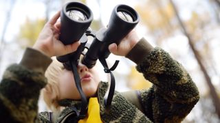 A child holding one of the best binoculars for kids in a forest