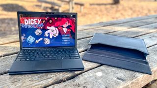 Asus Zenbook 17 Fold OLED review unit on picnic table with Dicey Dungeons running, carrying sleeve nearby