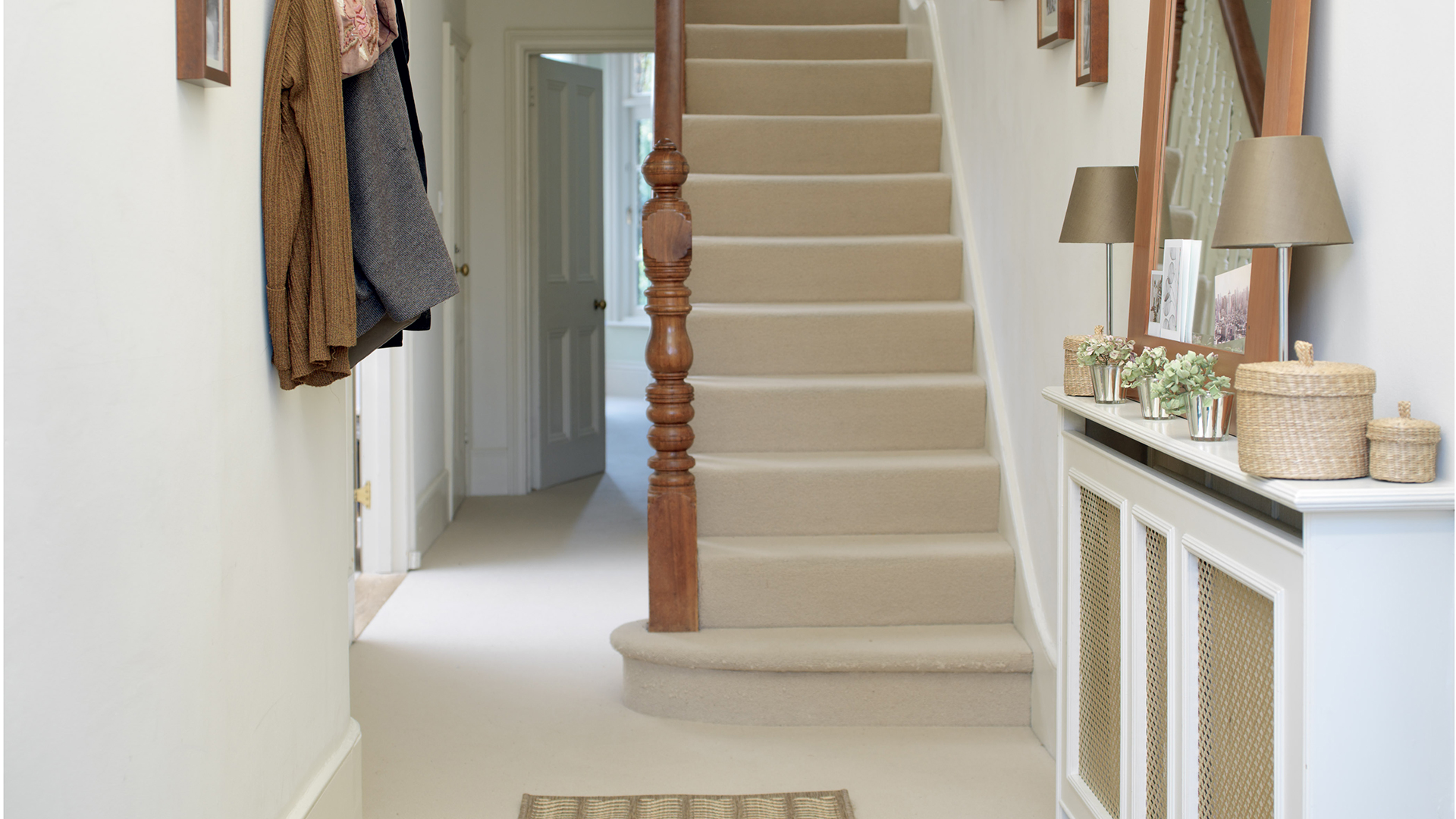 white and beige hallway with carpeted stairs and a wooden staircase