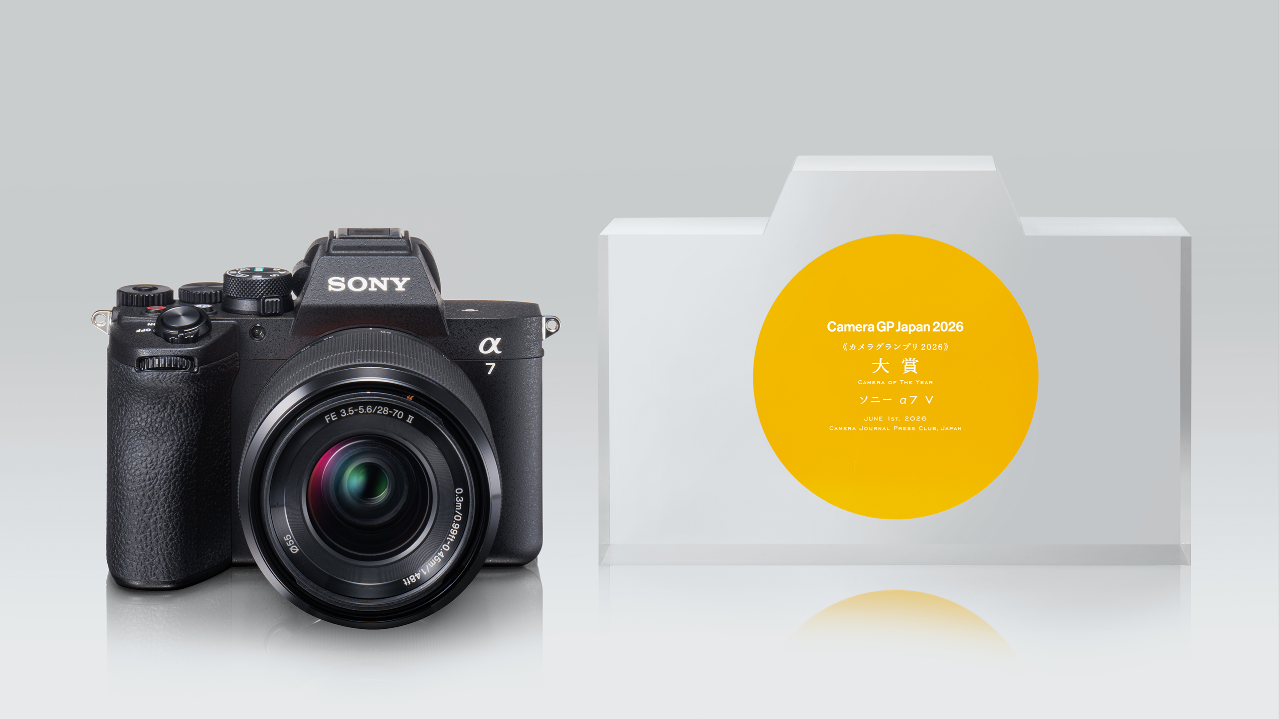 Sony Alpha 7 camera with a lens next to a Camera GP Japan 2026 award shaped like a camera, featuring a yellow circular label