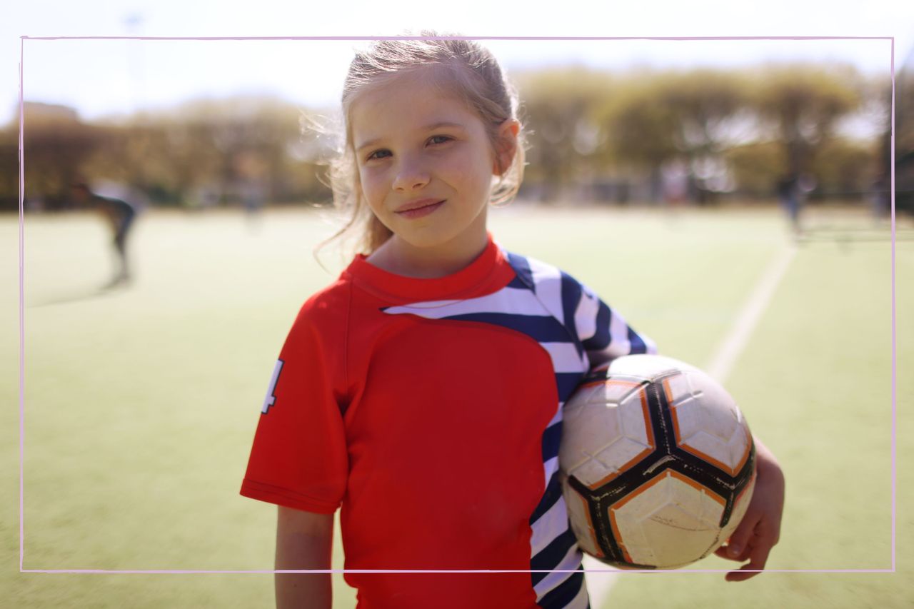 A young girl posing with a football under his arm