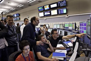 Scientists watch particle collision data inside the LHC control room.