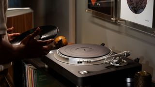 Denon DP-3000NE lifestyle image featuring a man placing a record on a turntable.