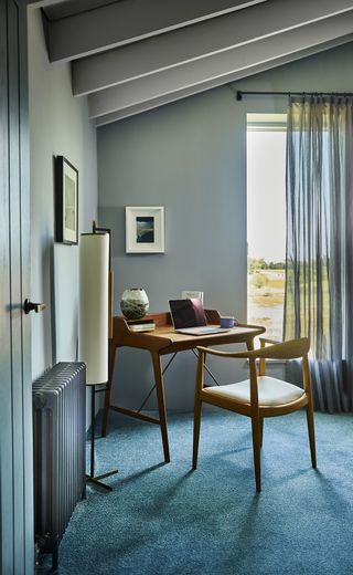 home office with gray walls, blue carpet, mid century modern desk and chair, floor lamp, artwork