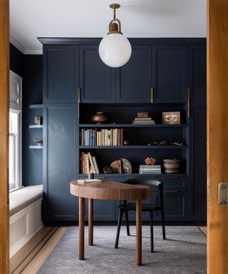 A navy blue and wood home office with styled bookshelves