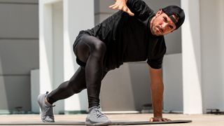 Young sportsman warming up with spider lunge exercise outdoors on building rooftop floor