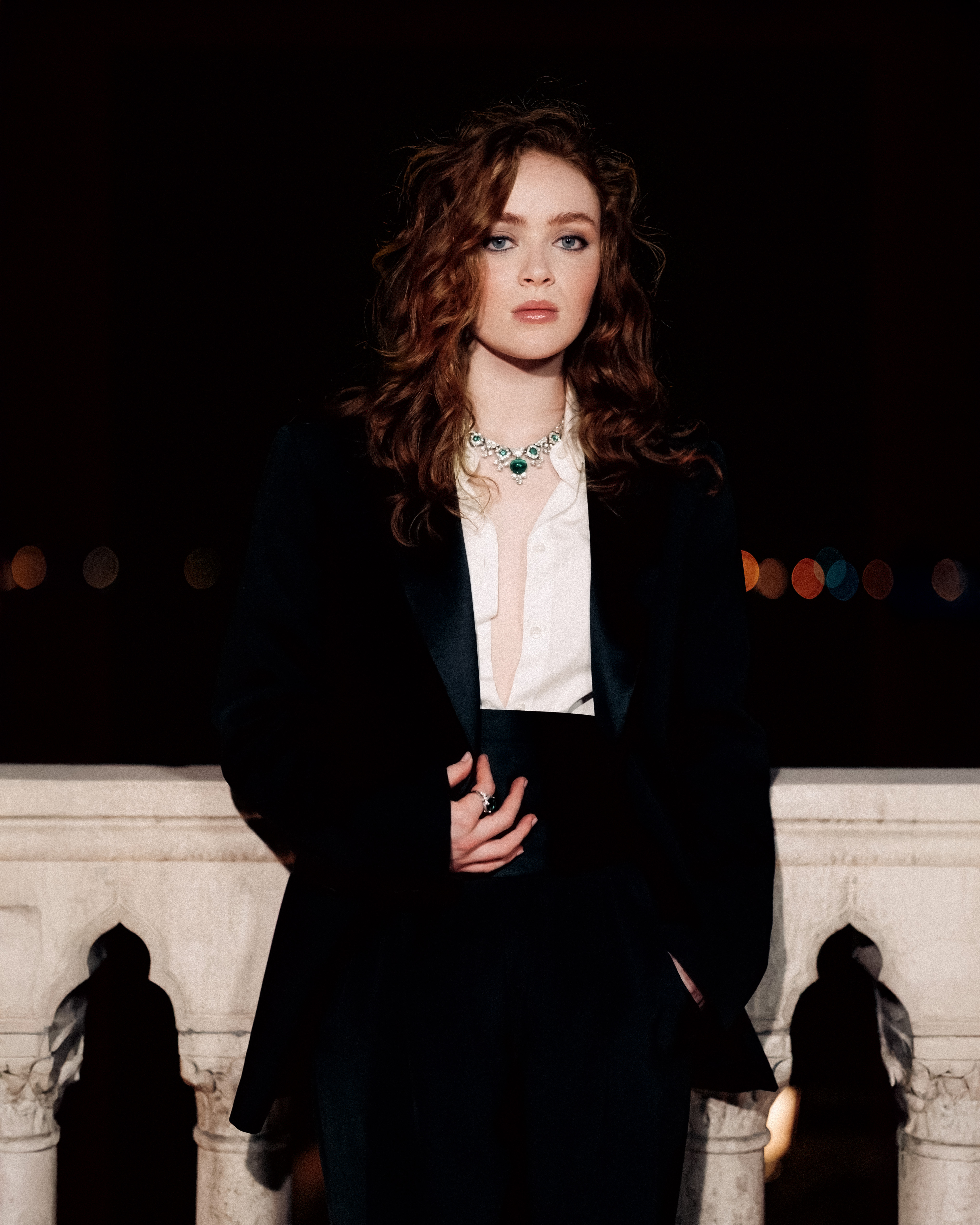 Sadie Sink stands on a bridge in venice wearing an armani suit with bulgari jewelry