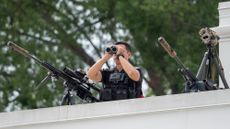 A Secret Service counter sniper guards the White House rooftop.