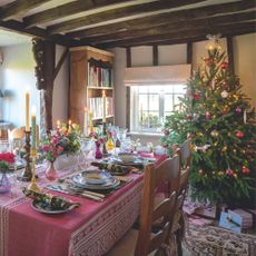 Decorated Christmas tree next to dining table with red tablescaping