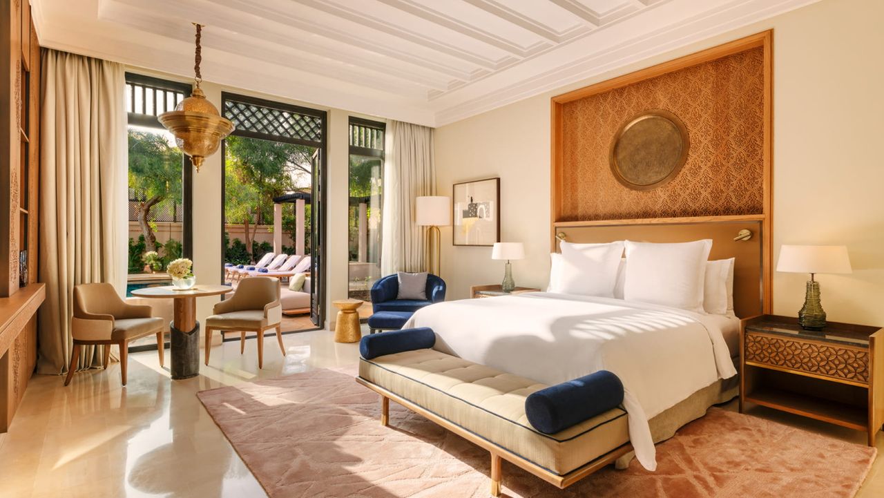 Image of a white bedroom with orange and wood accents there is a door leading to a private outdoor pool.