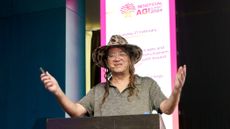 Ben Goertzel stands behind a lectern at Beneficial AGI Summit 2024