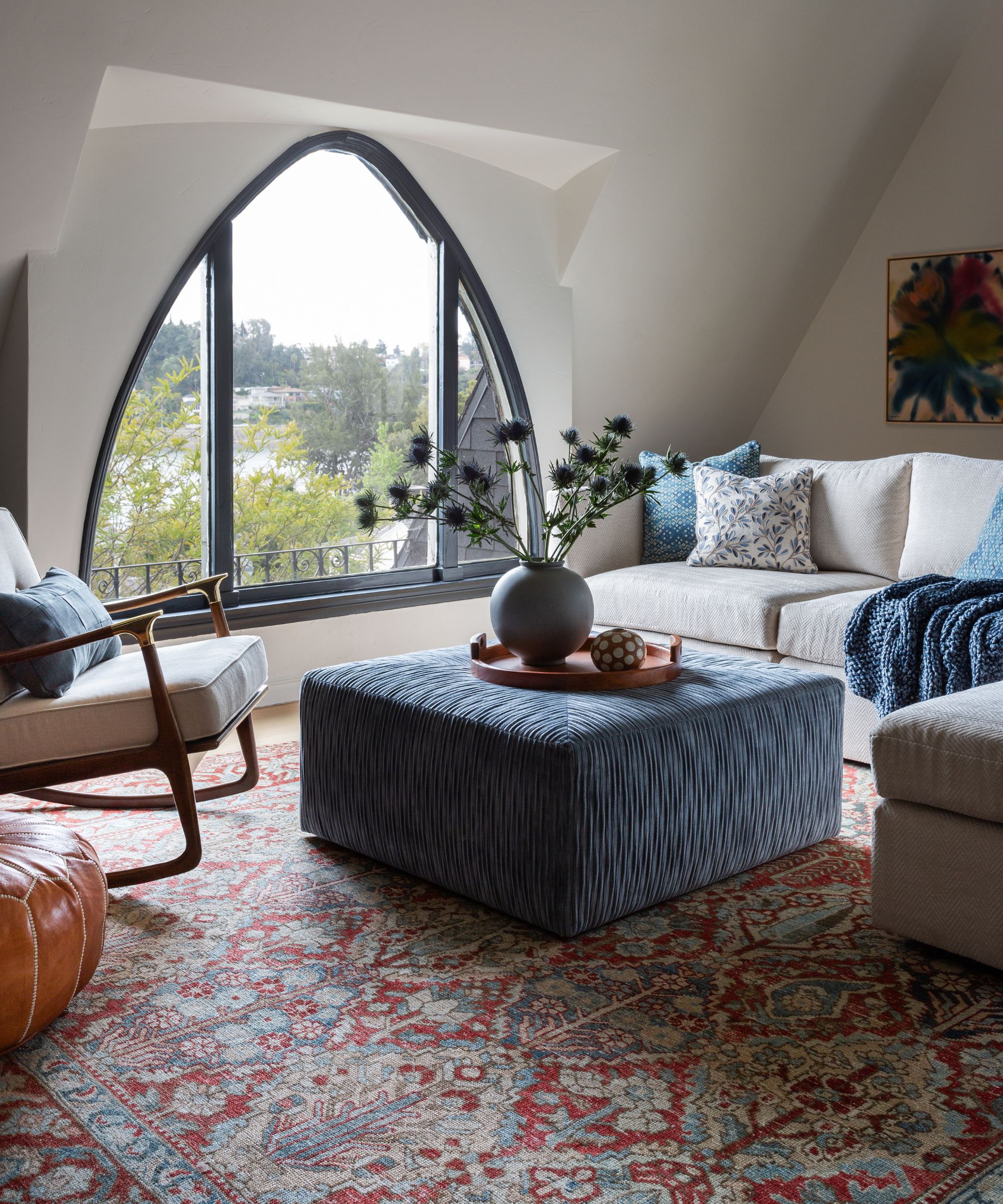 an LA home with an upstairs vaulted ceiling family room with a unique arrow shaped window and a corner couch
