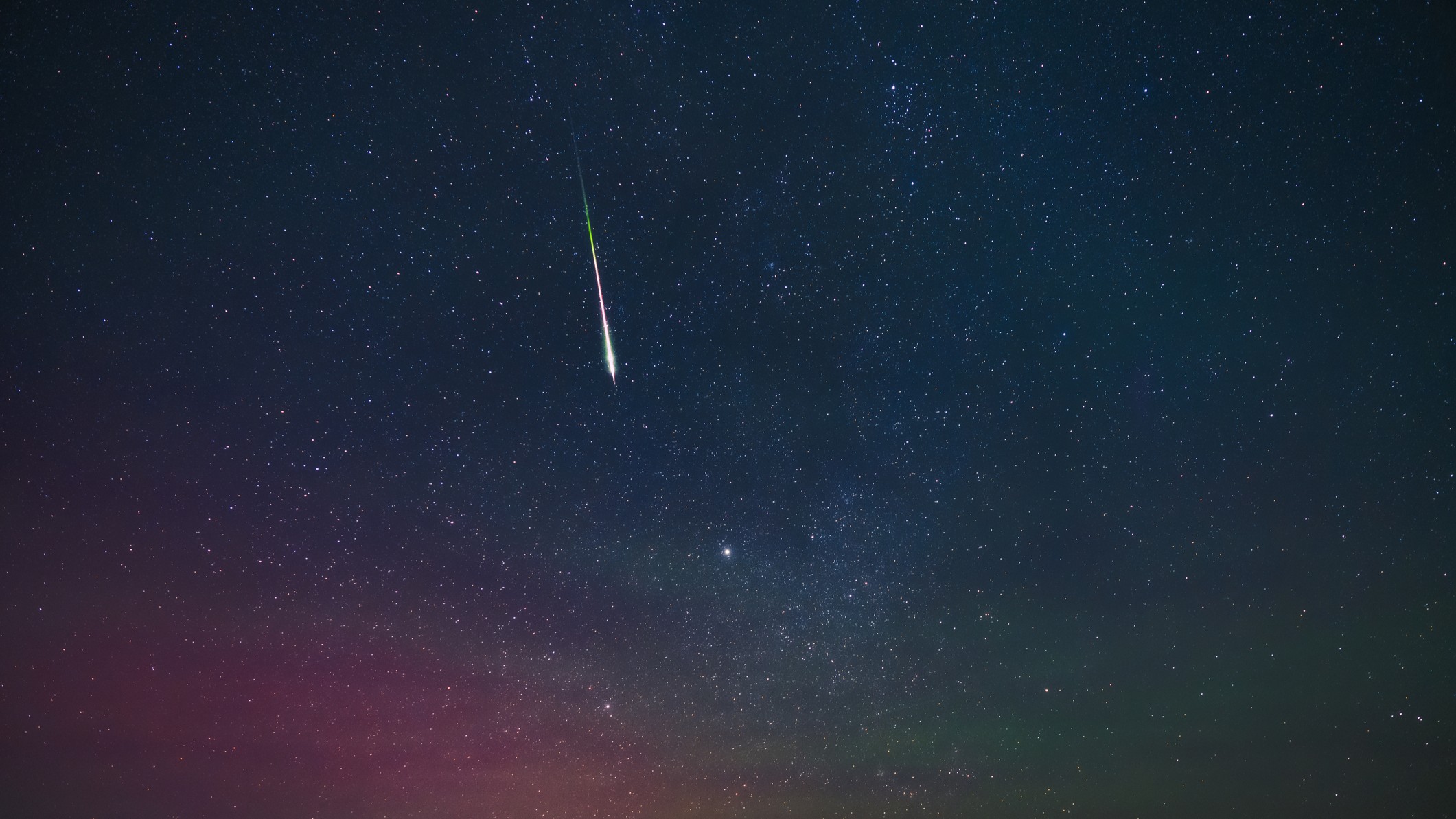 bright shooting star with a long train streaking through the star studded sky.