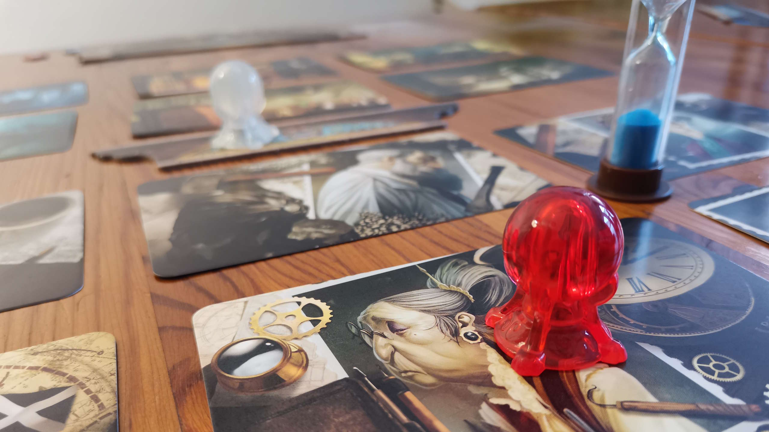 Mysterium tokens on character cards, with a sand timer visible on a wooden surface