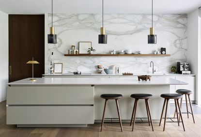 White kitchen with large island and marble backsplash