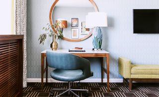 Laurel Inn guestroom showing brown work desk, brown mirror and blue chair