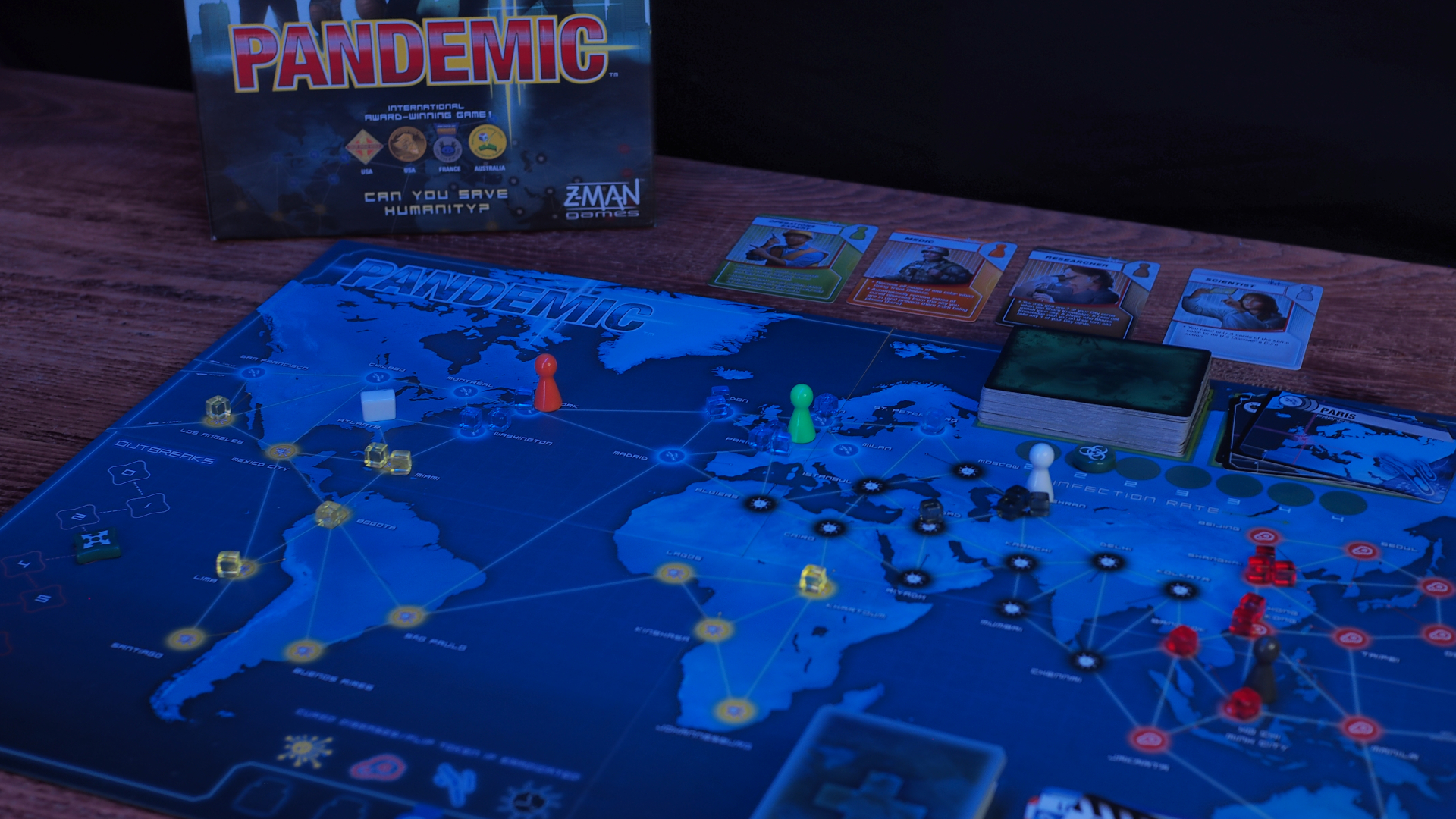 The Pandemic board with tokens, cards, and box arrayed on a wooden table