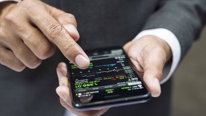 A man looking at a stock app on his phone.