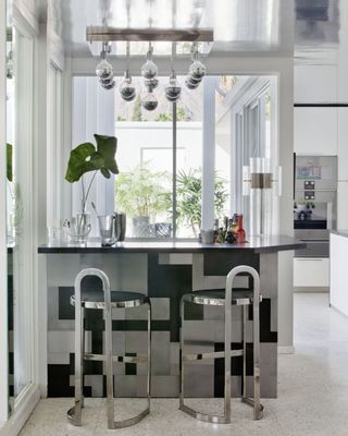 A home bar in a corner, with multiple lighting pieces hung above the counter