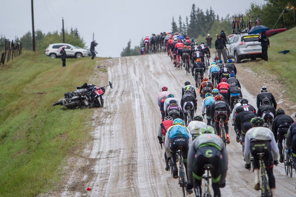 A moto falls on the muddy shoulder of one of todays dirt sections