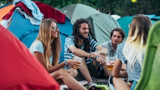 Four people drink beer in front of their tents