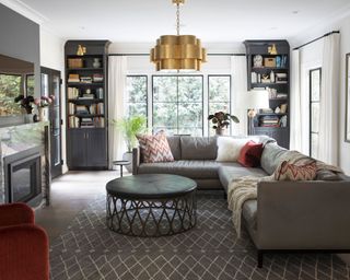 Modern family room with sofa, round coffee table, matching alcove shelving, gold pendant light