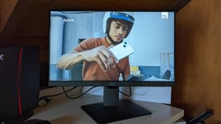 BenQ GW2785TC in a home office showing a video of a man wearing a helmet and holding a camera