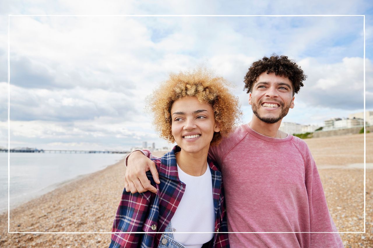 Couple on a beach with the man putting his arm around the woman