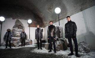 Five men stood in tunnel with snow on the floor wearing coats