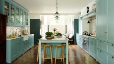 A kitchen with light blue cabinets, white countertops, white walls, and wooden counter stools