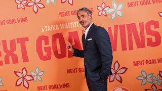 Taika Waititi pulls a funny face as he points at the Next Goal Wins movie logo during the film's premiere